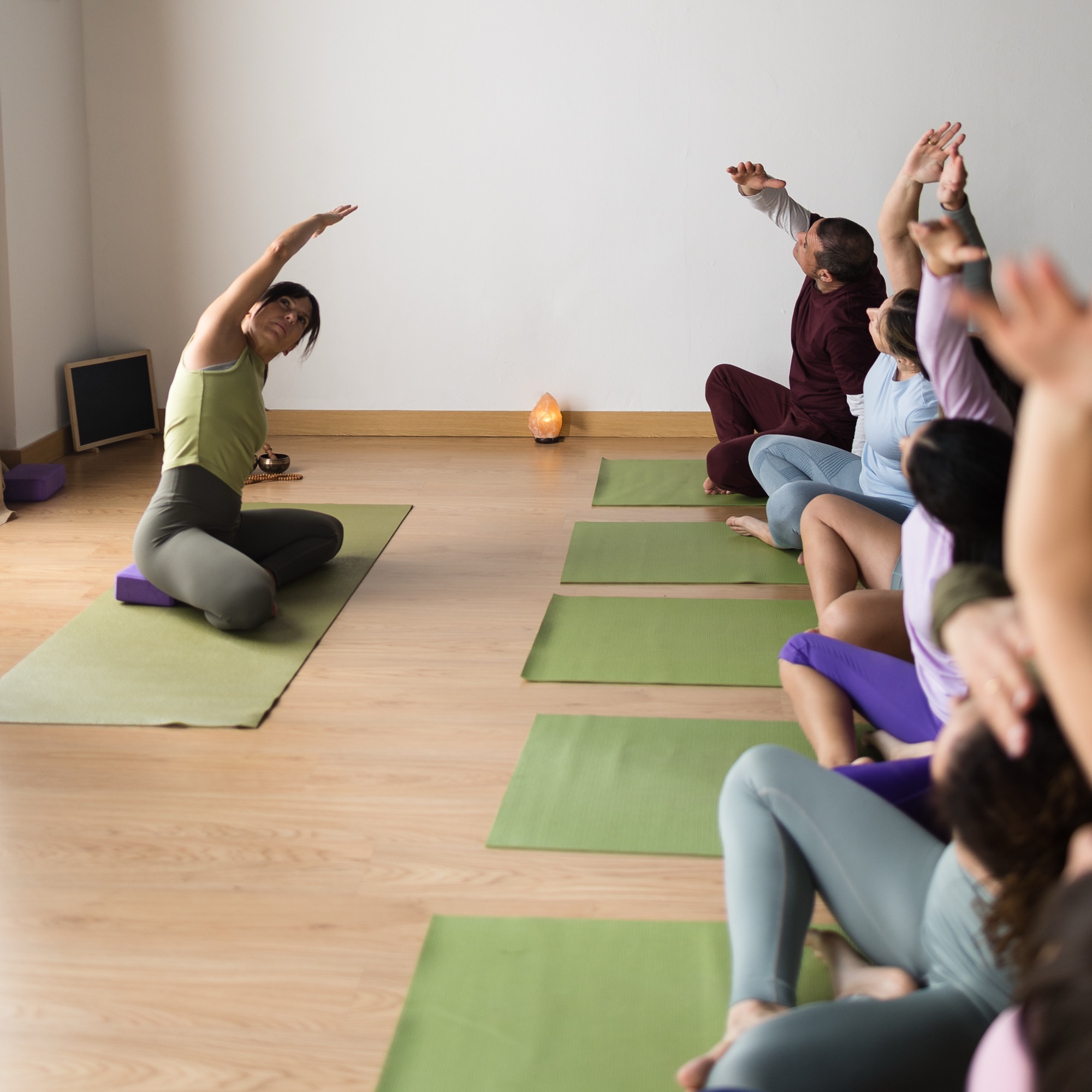 A warm studio class stretching together into a side bend