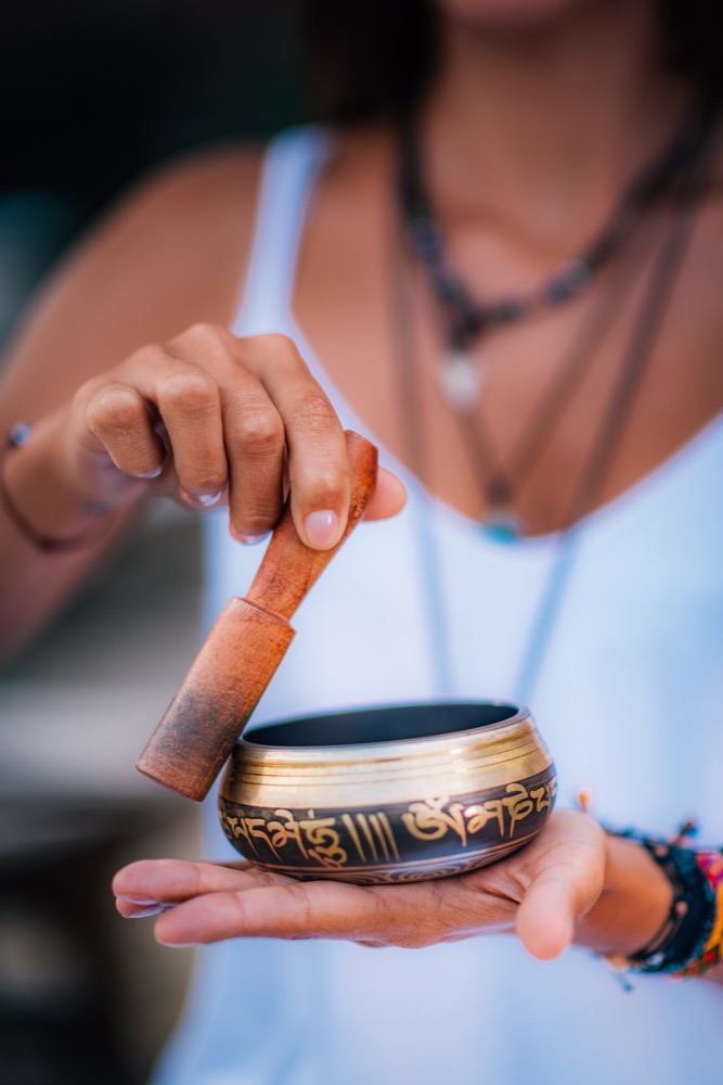 Hands holding a Tibetan singing bowl and striker